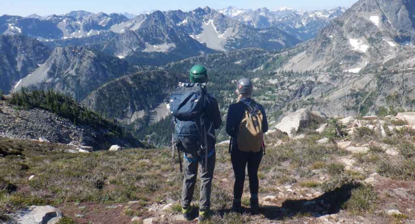 two people overlook a vast mountainous landscape on an outward bound gap year course